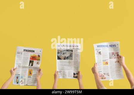 Women with newspapers on yellow background Stock Photo
