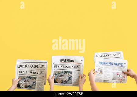 Women with newspapers on yellow background Stock Photo