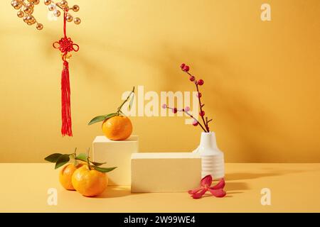 Tangerines, two wooden platforms, a flower vase and Tet decorations are displayed on a yellow background. Ideal space for displaying products during T Stock Photo