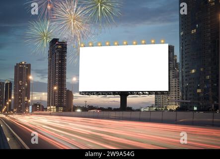 Blank billboard on the highway during the twilight with city background And fireworks in the sky with clipping path on screen.- can be used for displa Stock Photo