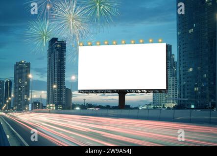 Blank billboard on the highway during the twilight with city background And fireworks in the sky with clipping path on screen.- can be used for displa Stock Photo