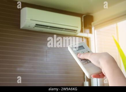 Hand hold remote control directed on the air conditioner Stock Photo