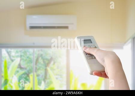 Hand hold remote control directed on the air conditioner Stock Photo