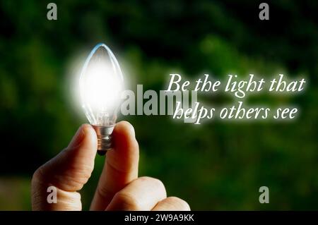 Motivational quote about being the light that helps others see with closeup light bulb background Stock Photo