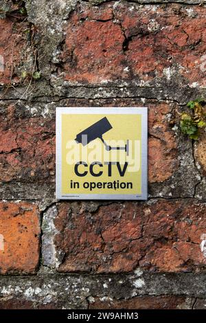Yellow CCTV sign on a red brick wall Stock Photo