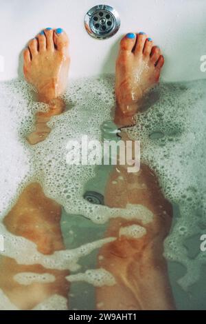Woman relaxing in a bubble bath with blue toe nails Stock Photo