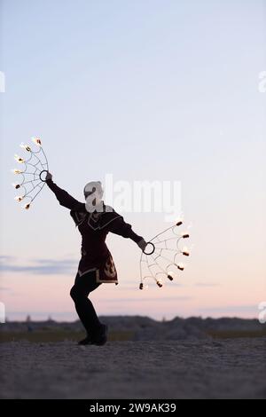 Vertical full length portrait of young woman as fire show performer wearing costume and dancing outdoors in nature Stock Photo