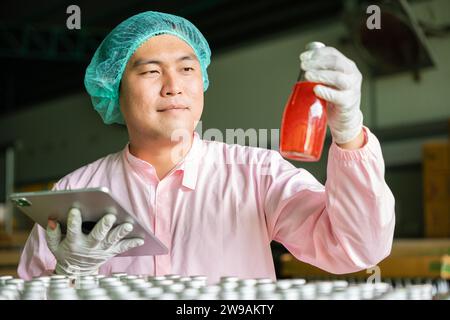 Inspector verifies bottled products on conveyor belt in beverage factory maintaining high quality Stock Photo