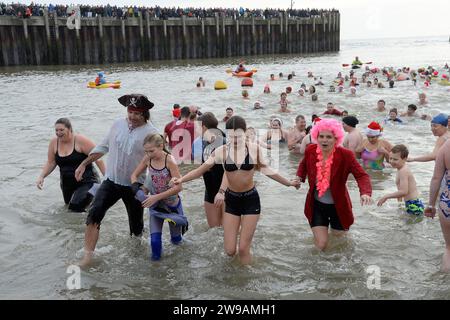 West Bay, Dorset, UK.  26th December 2023.  UK Weather:  Over one hundred and fifty swimmers in fancy dress take part in the annual West Bay Wallow Boxing Day swim at West Bay in Dorset which was supported by huge crowds on a warm overcast day.  Picture Credit: Graham Hunt/Alamy Live News Stock Photo