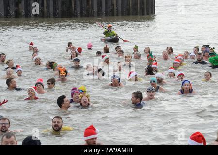 West Bay, Dorset, UK.  26th December 2023.  UK Weather:  Over one hundred and fifty swimmers in fancy dress take part in the annual West Bay Wallow Boxing Day swim at West Bay in Dorset which was supported by huge crowds on a warm overcast day.  Picture Credit: Graham Hunt/Alamy Live News Stock Photo