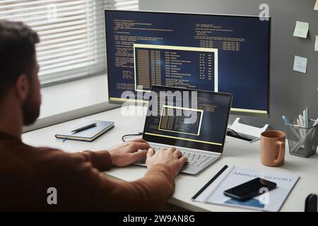 Over shoulder view of software programmer using computer in office and writing code, copy space Stock Photo