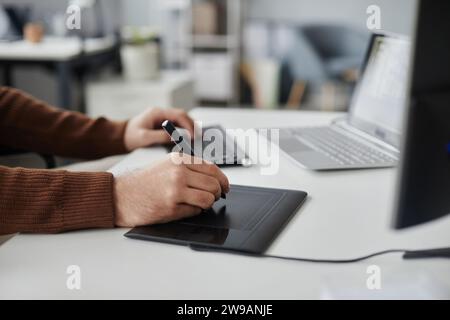 Side view closeup of unrecognizable man using pen tablet while editing photo or video at office workplace, copy space Stock Photo