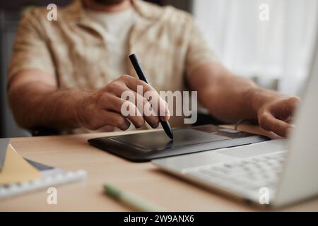 Close up of male hands using pen tablet while editing photos or video at home office, copy space Stock Photo
