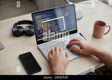Close up of male hands typing at laptop keyboard and writing code at home office workplace, copy space Stock Photo