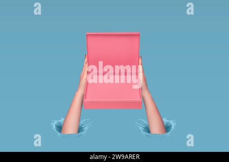 Woman's hands holding pink gift box on a pastel blue background. Ink splashes. Splashes of blue paint. Copy space. Creative gift giving concept. Stock Photo