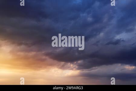 Dramatic sunset sky with dark rainy clouds and bright sunshine. Stock Photo