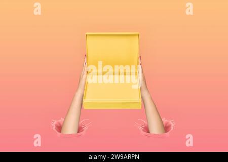 Woman's hands holding yellow gift box. Ink splashes. Pastel colors. Splashes of paint. Copy space. Creative gift giving concept. Stock Photo