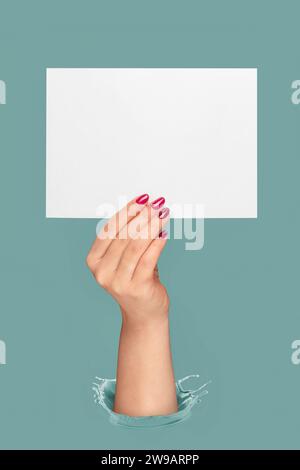 Female hand holding empty paper on pastel blue background. Copy paste image for text. Stock Photo