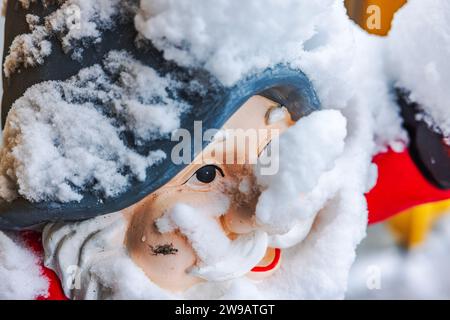 Close-up view of snow-covered gnome face for outdoor decoration at entrance of house on frosty winter day. Stock Photo