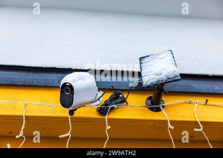 Outdoor surveillance with snow-covered solar panel on facade of villa. Sweden. Stock Photo