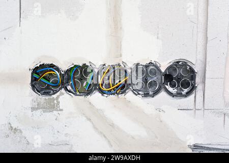Boxes with cables for electric sockets installed in new house building empty wall. Stock Photo