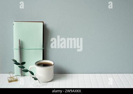 Workspace with diary notebook, pen, coffee on white tile desk. gray wall background Stock Photo