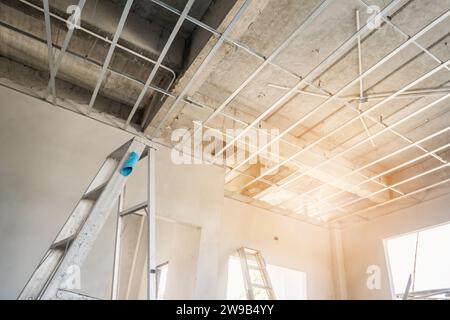 Install metal frame for plaster board ceiling at house under construction Stock Photo