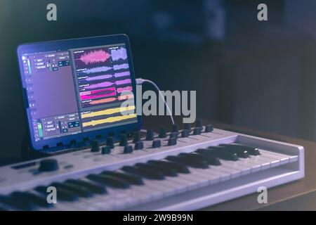 Musical keyboard and tablet in a dark room, music production. Stock Photo