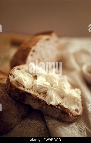 Close up photo of pieces of delicious, hot homemade loaf of bread with fresh homemade butter lying in natural fabric on wooden table. Stock Photo