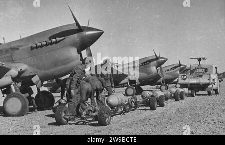 Item Trolley loads of bombs ready for loading on fighter bombers at an advanced landing ground in Tripolitania. (Curtiss P-40's). The activities of fighter bombers have been the principal feature of Allied air attacks in the present offensive in Libya 1943 Stock Photo