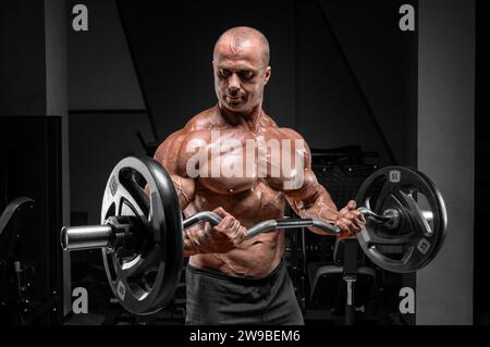 Professional weightlifter posing in the gym with a barbell in his hands. Classic bodybuilding. Mixed media Stock Photo