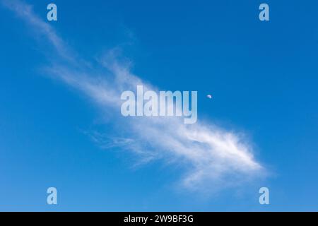 Single white cloud in blue sky with half moon Stock Photo