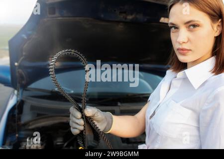 Young beautiful and hot woman auto mechanic holding a timing belt in her hands, car breakdown Stock Photo