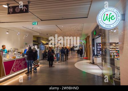 Christmas interior of shopping center featuring festive cafe and various boutiques. Stock Photo