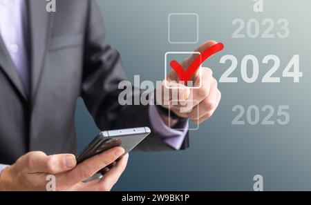 man hand touching on 2024 calender year button on digital virtual screen blur background Stock Photo