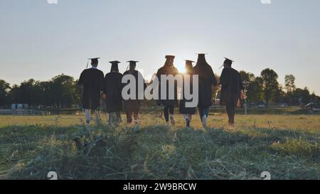 Graduate students walking through an evening meadow at sunset. Stock Photo