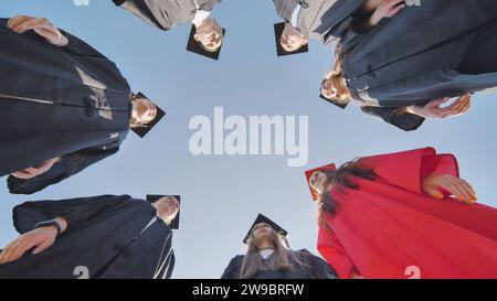 Graduates in robes stand in a circle. View from below. Stock Photo