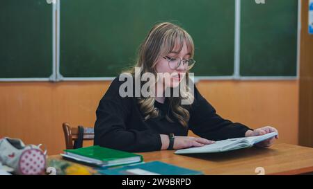 A schoolgirl in the role of a teacher sits at her desk Stock Photo - Alamy