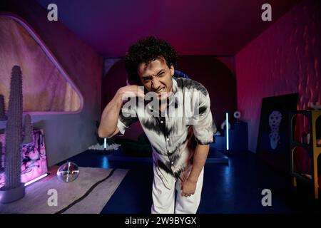 Stylish young man confidently posing in modern art space with neon lights and artworks Stock Photo
