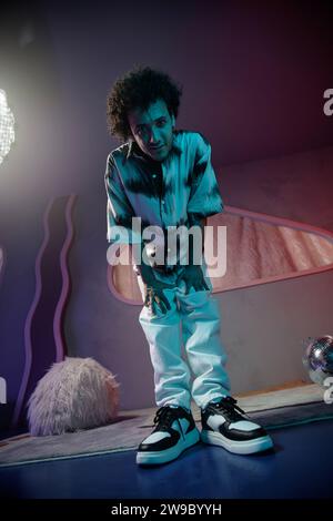 Young man standing with hands on knees looking down at camera posing in contemporary art space Stock Photo