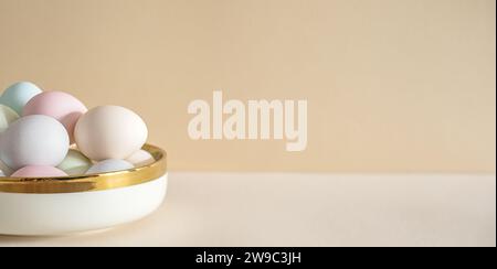 Pastel colored Easter eggs in white bowl on a table Stock Photo