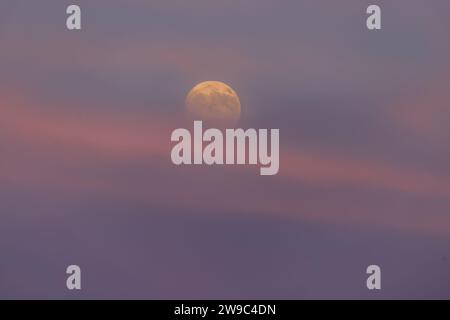 The buck moon rising in the early evening sky. Stock Photo