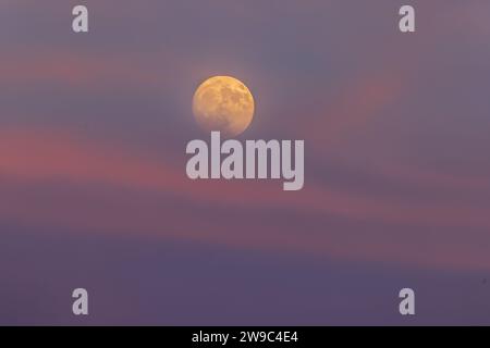 The buck moon rising in the early evening sky. Stock Photo