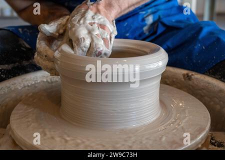 Potter throwing a pot on the wheel in a studio. High quality photo. Hobby, side hustle, activity Stock Photo