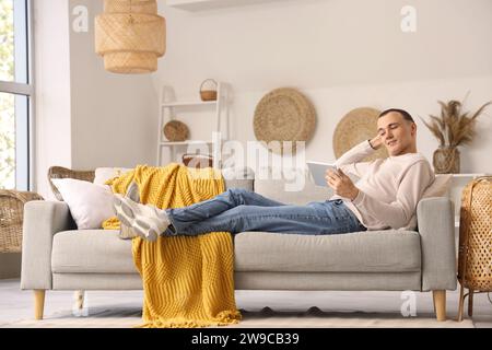 Young man using tablet computer on sofa at home Stock Photo