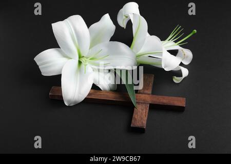 Beautiful lily flowers and cross on black background Stock Photo