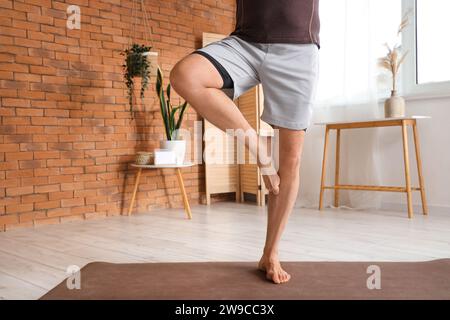 Mature man doing yoga on mat at home Stock Photo