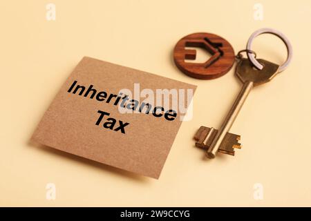 Inheritance Tax. Card and key with key chain in shape of house on beige background, closeup Stock Photo