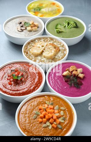 Different cream soups and tasty broth in bowls on table, closeup Stock Photo