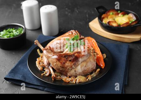 Tasty cooked rabbit meat with vegetables served on black table Stock Photo
